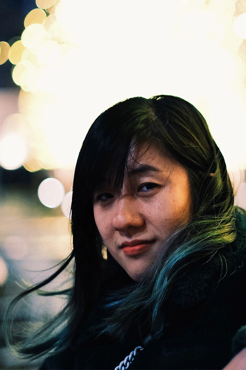 Portrait of a woman looking behind her shoulder against bokeh effect lights.